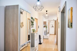 A modern hallway with a wooden cabinet, a mirror, a potted plant, and a hanging light fixture. - Central Monarh Tower Accomodation (Timișoara)