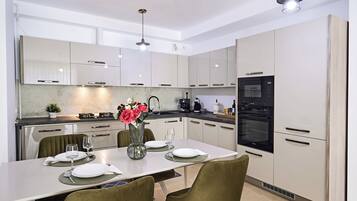 A modern kitchen with white cabinets, a dining table set for four, and a vase with flowers.