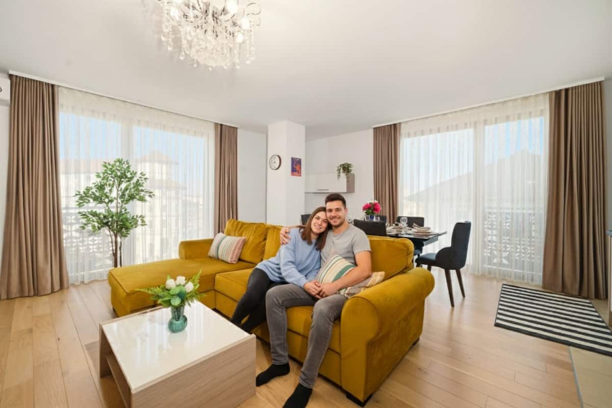 Un salon moderne avec un canapé jaune, une table basse en bois et un coin repas comprenant une table et des chaises.