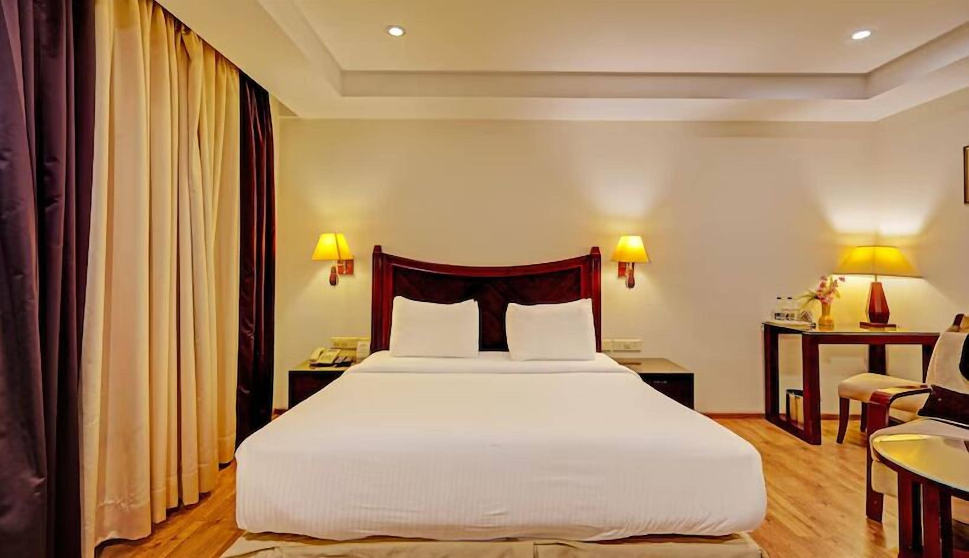 Ein Hotelzimmer mit einem großen Bett, zwei Nachttischen, einem Schreibtisch und einem Sessel.