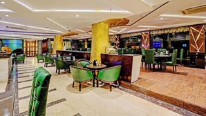 Eine moderne Hotelhalle mit grün gepolsterten Sesseln, einem Empfangstresen und einer Bar.