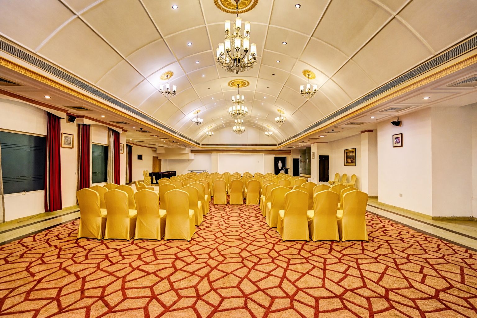 A conference room with rows of chairs, a patterned carpet, and a chandelier.