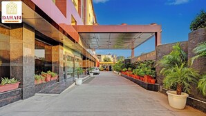 Ein moderner Hotelzugang mit überdachtem Gang, Blumentöpfen und blauem Himmel.