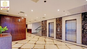 Eine Hotellobby mit Rezeption, Marmorböden, Aufzügen und einer Treppe.