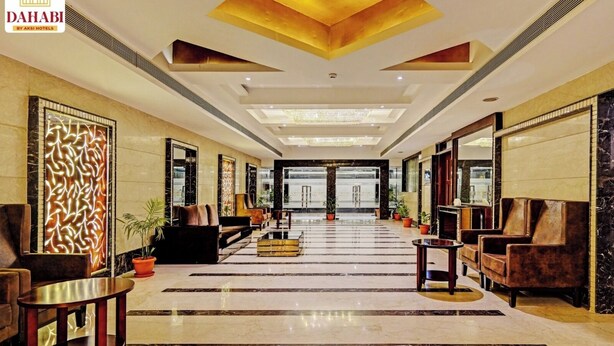 Eine großzügige Lobby mit modernem Design, inklusive einer zentralen Sitzecke mit Sofas und Sesseln, einer Wand mit Muster und einem großen Spiegel.