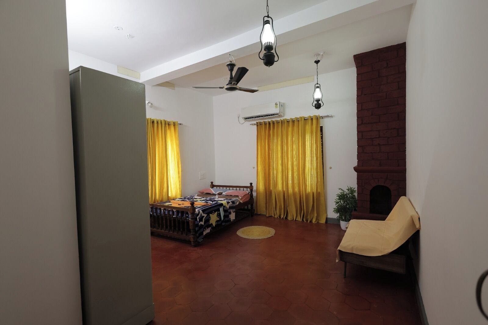 A room with a bed, a chair, a fireplace, and a ceiling fan.