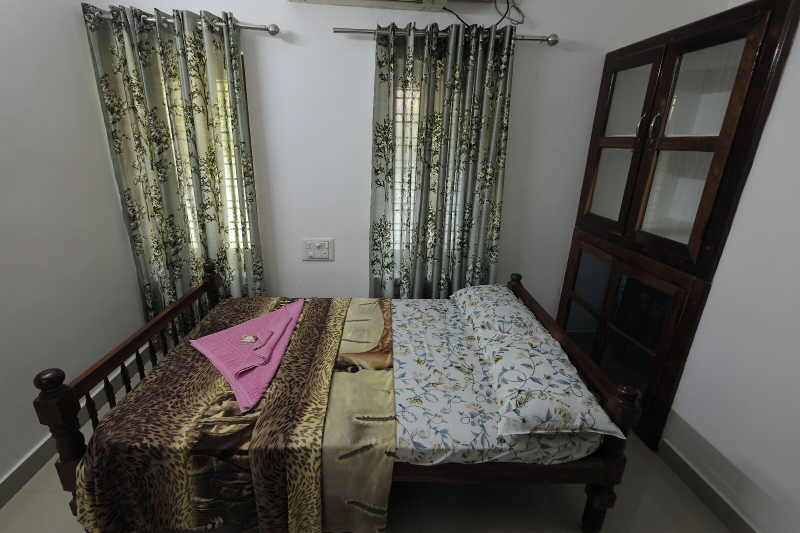 A bedroom with a bed, a wooden headboard, a window with curtains, and a door.