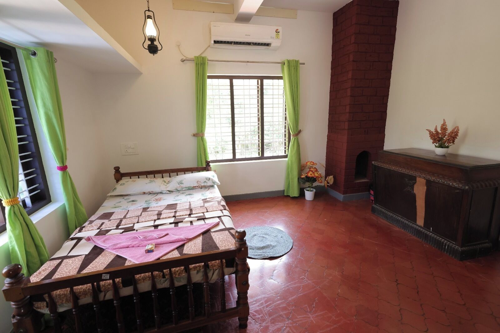 Un dormitorio con cama de madera, cortinas verdes, chimenea y una planta en maceta.
