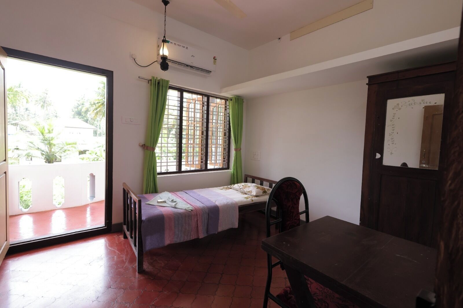 A small room with a bed, a table, and a window with curtains.