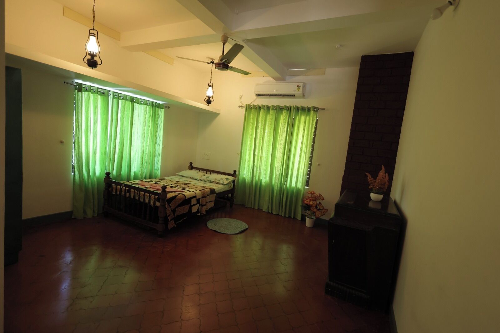 Un dormitorio con cama, cortinas verdes, ventilador de techo, aire acondicionado y chimenea.
