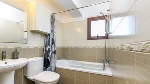Une salle de bain comprenant des toilettes, un lavabo, une baignoire et une douche.