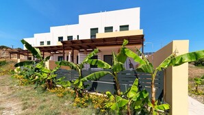 Un edificio moderno de dos pisos con techo plano y una pérgola de madera en la fachada.