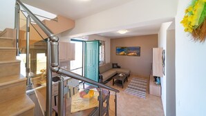 Un apartamento moderno con una escalera, una sala de estar con sofá y mesa de centro, y una zona de cocina.