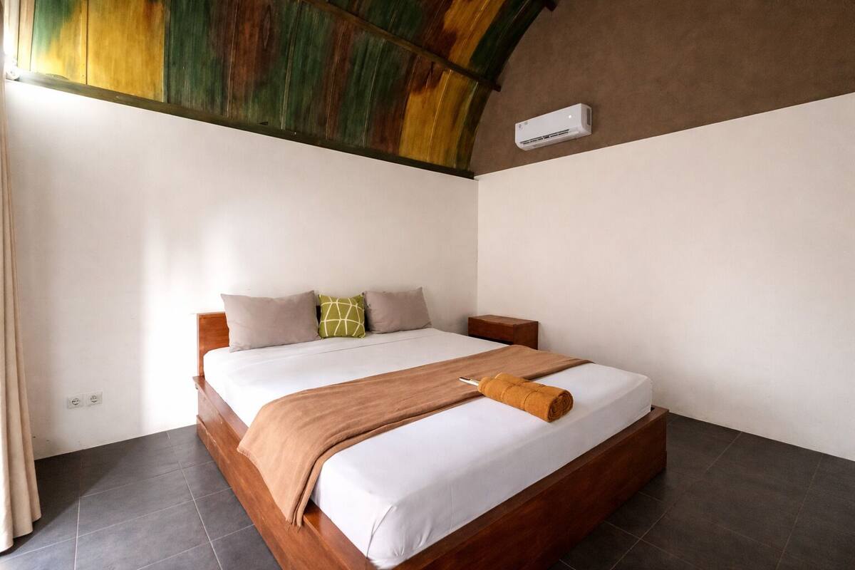 A bedroom with a wooden bed, white bedding, and a brown blanket.