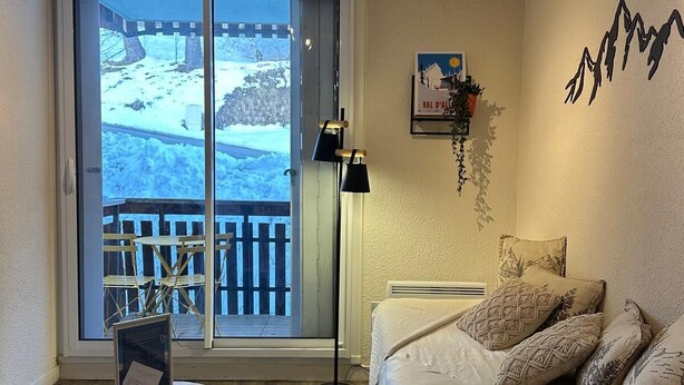 Une pièce confortable avec un lit, un bureau et une vue sur un espace extérieur enneigé, visible à travers une porte coulissante.