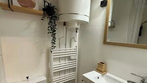 Une petite salle de bain comprenant des toilettes, un lavabo et un miroir.