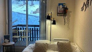 Une chambre dotée d’un grand lit, d’une porte-fenêtre coulissante donnant sur un balcon, d’une petite table et d’une lampe fixée au mur.