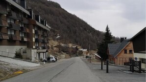 Une rue bordée d’immeubles, dont un bâtiment à plusieurs étages doté de balcons et un autre, plus petit, avec un toit en pente.