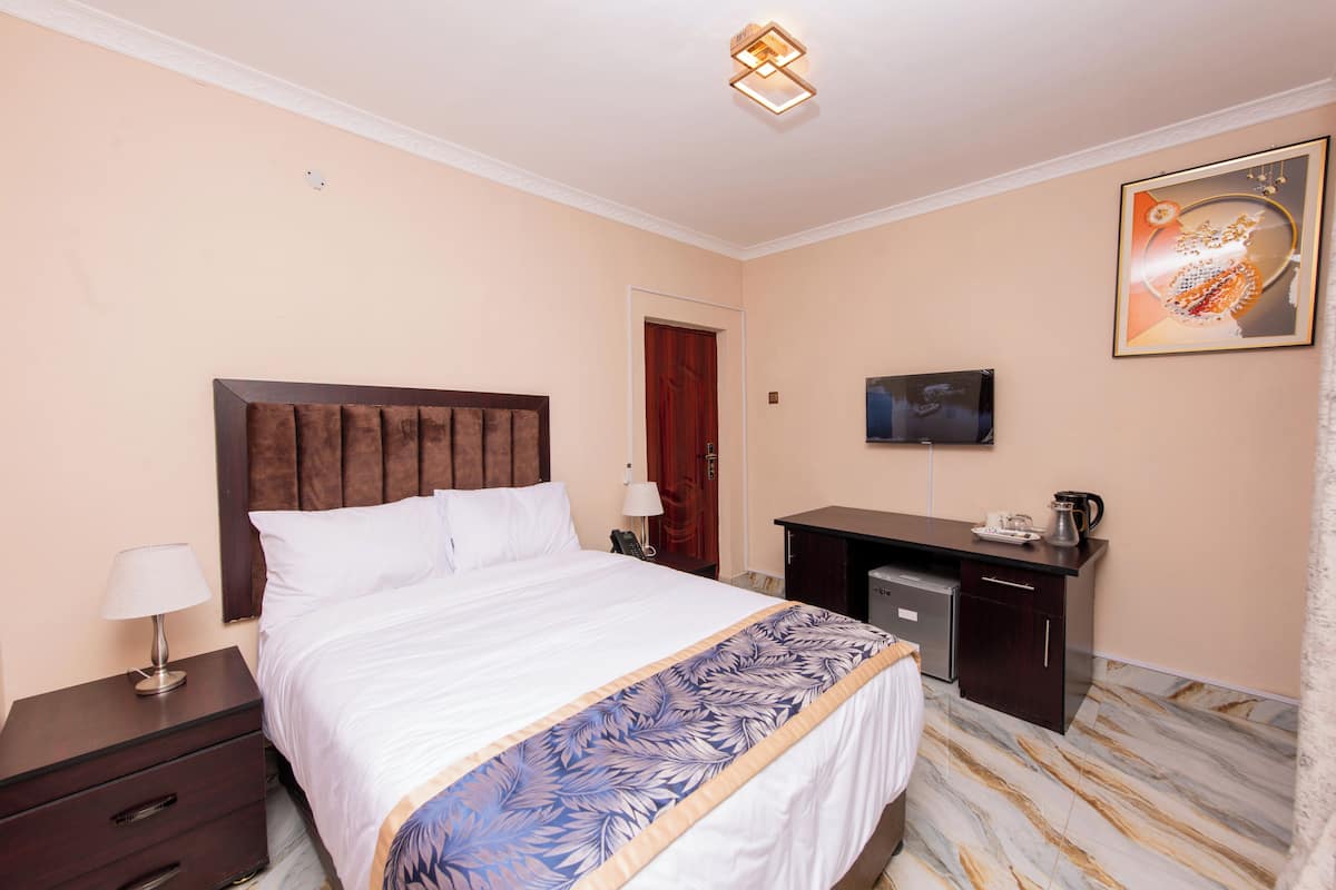 A hotel room with a large bed, a desk, a television, and a coffee maker.