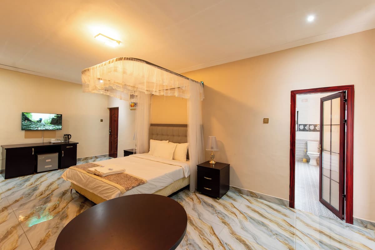 A hotel room with a bed, bedside table, TV, and a view of the bathroom.