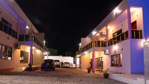 A modern hotel with a courtyard, featuring a covered car parking area and a two-story building with balconies. - Lavish Suites (Blantyre)