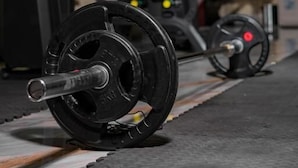A gym with weightlifting equipment, including a barbell and weight plates. - Lavish Suites (Blantyre)