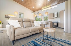 Ein modernes Wohnzimmer mit einem beigen Sofa, einem runden Couchtisch und einem blau gestreiften Teppich.