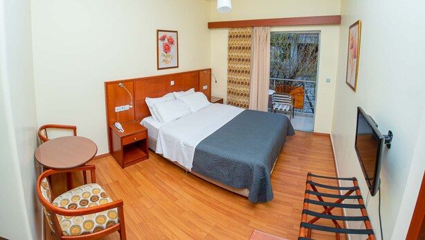 A hotel room with a bed, a desk, a chair, a TV, and a balcony with a view. - Hotel Ena - Stylish Mountain View Suite With Pool (Lamia)