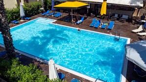 A swimming pool with blue water, surrounded by lounge chairs and umbrellas. - Hotel Ena - Stylish Mountain View Suite With Pool (Lamia)