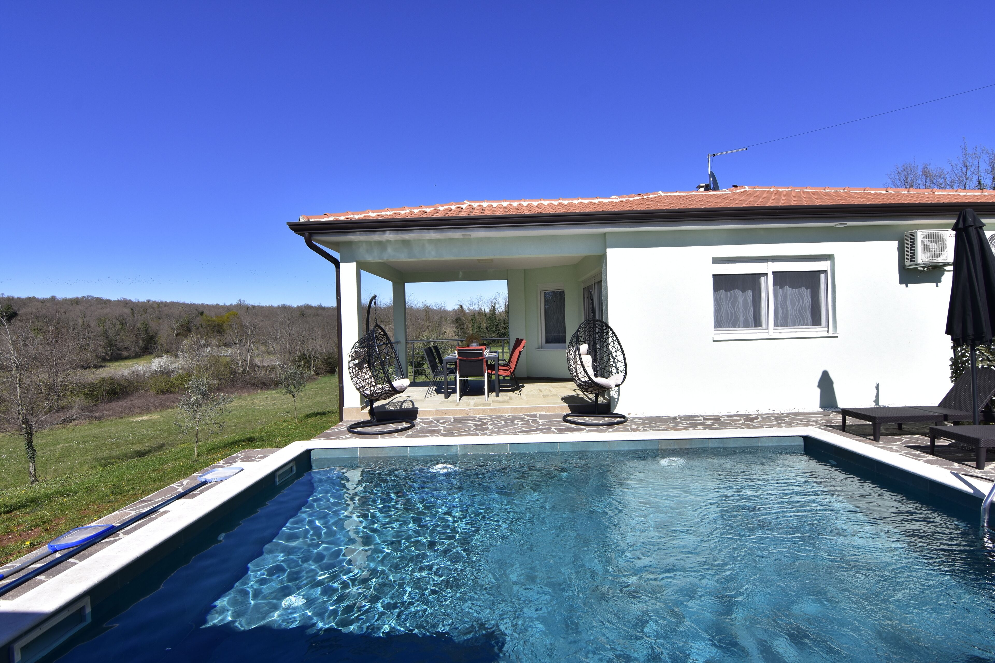 Una piscina con zona de terraza, una mesa y sillas.