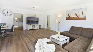 A modern living room with a brown sofa, a white coffee table, a clock, and a flat-screen TV. - Comfortable Holiday Home With Pool (Buje)