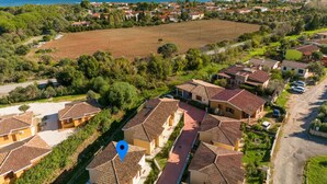 Un quartier résidentiel avec des maisons aux toits de tuiles, une vue dégagée sur la mer et un grand champ ouvert.
