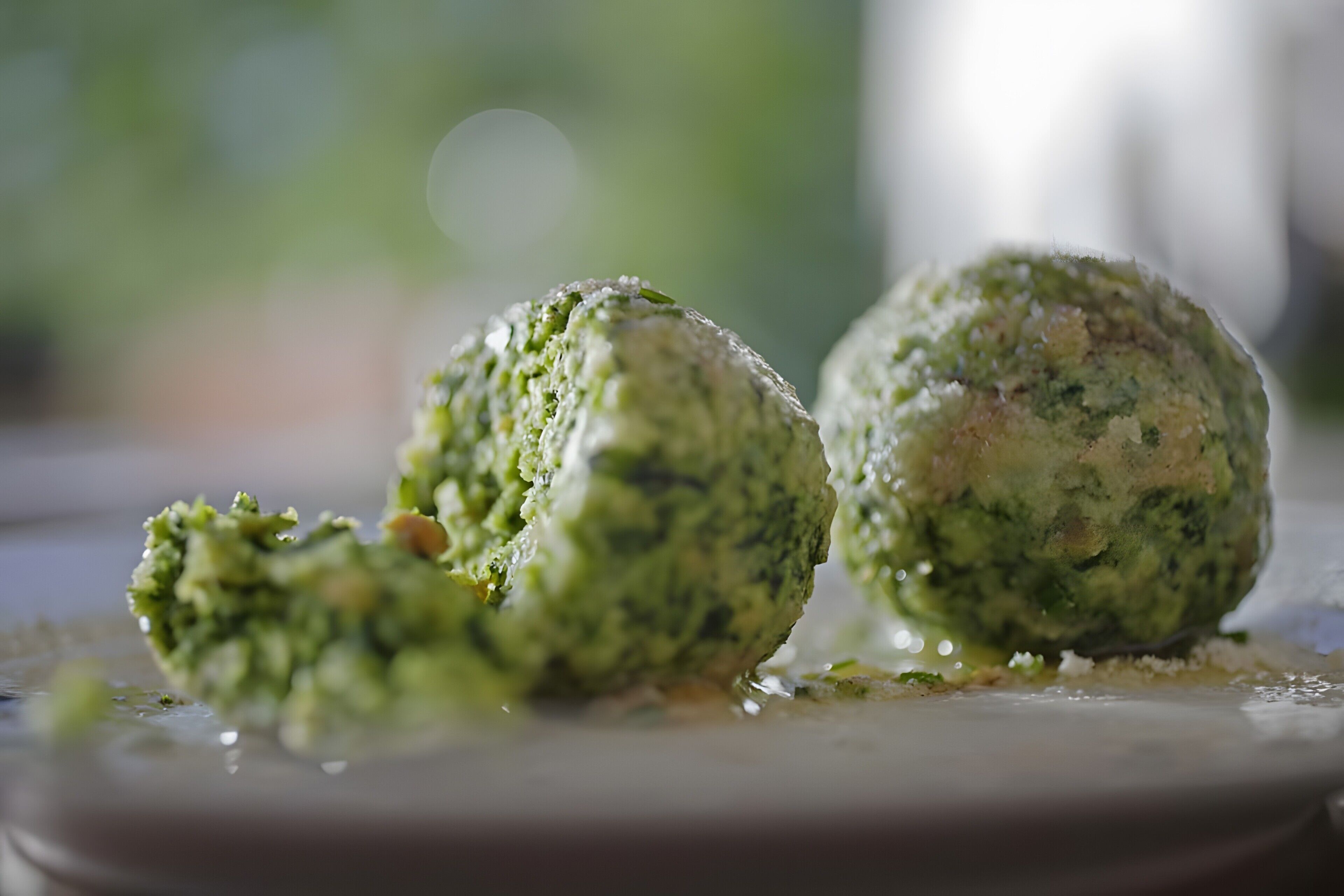 Dos alimentos verdes en un plato con un fondo desenfocado.