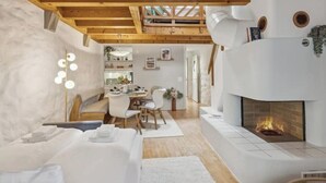 A modern interior with a fireplace, wooden beams, a dining area, and a cozy seating space. - Old Town Riverside | AC | Balcony | Free Parking | Water View (Zürich)