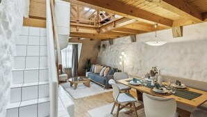 A modern interior with a wooden ceiling, a dining area with a table set for four, and a living area with a sofa and a coffee table. - Old Town Riverside | AC | Balcony | Free Parking | Water View (Zürich)