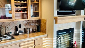 A modern kitchen with wooden cabinets, a built-in wine rack, a fireplace, and a flat-screen TV mounted above it. - Perfect 4-bedroom house near lakes and trails in Folsom (Folsom)