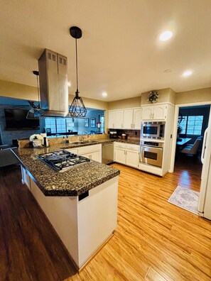A modern kitchen with a central island, stainless steel appliances, and wooden flooring. - Perfect 4-bedroom house near lakes and trails in Folsom (Folsom)