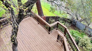 A wooden deck with a railing, surrounded by trees and a grassy area. - Perfect 4-bedroom house near lakes and trails in Folsom (Folsom)