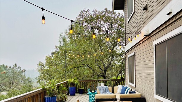 A wooden deck with a table and chairs, potted plants, and string lights. - Perfect 4-bedroom house near lakes and trails in Folsom (Folsom)