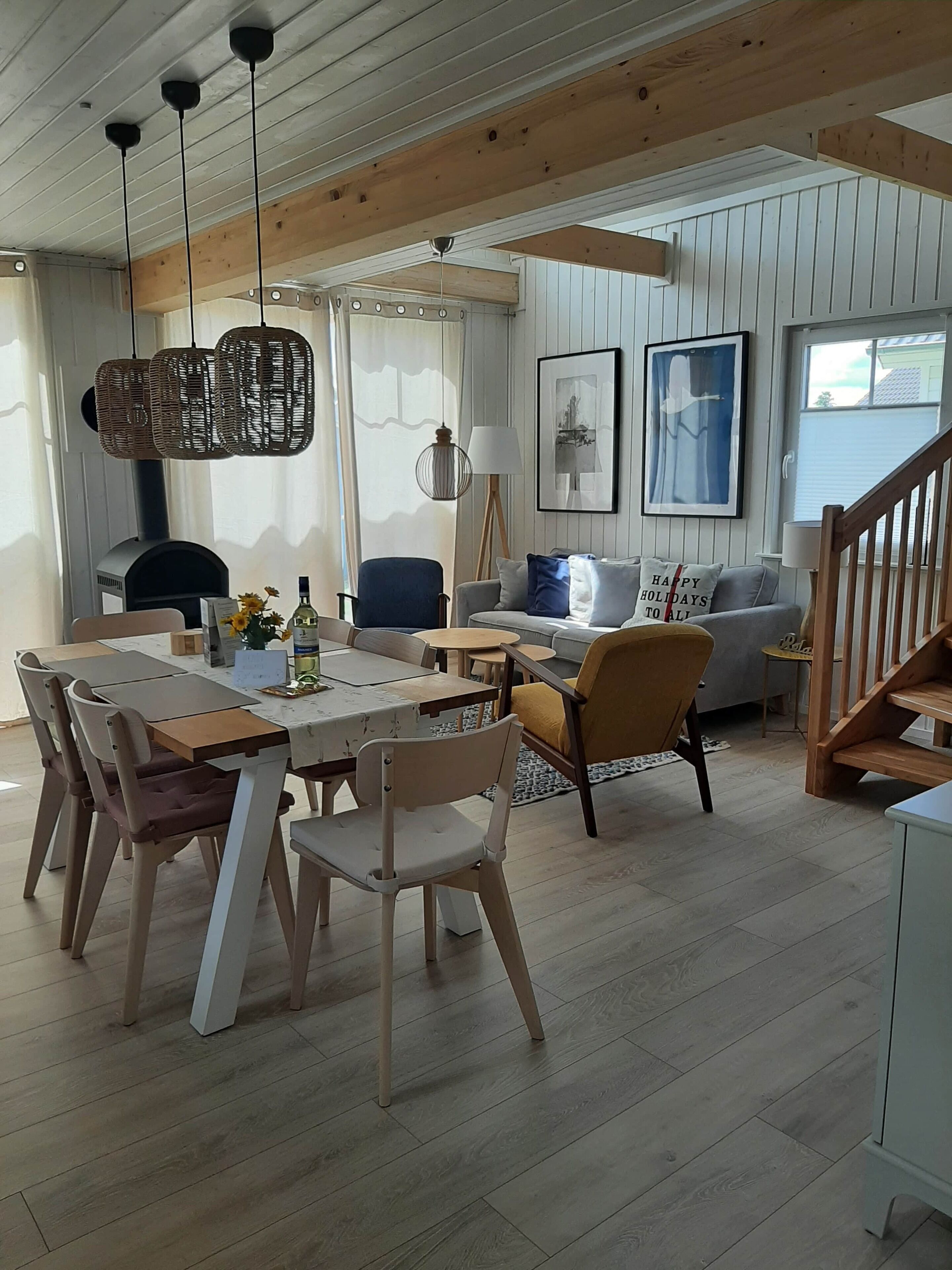 A cozy living room with a wooden dining table, chairs, a sofa, and a staircase.