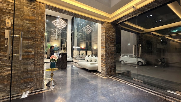 A lobby with a reception desk, a sofa, and a car parked outside. - Skyearth Hotel (Indore)