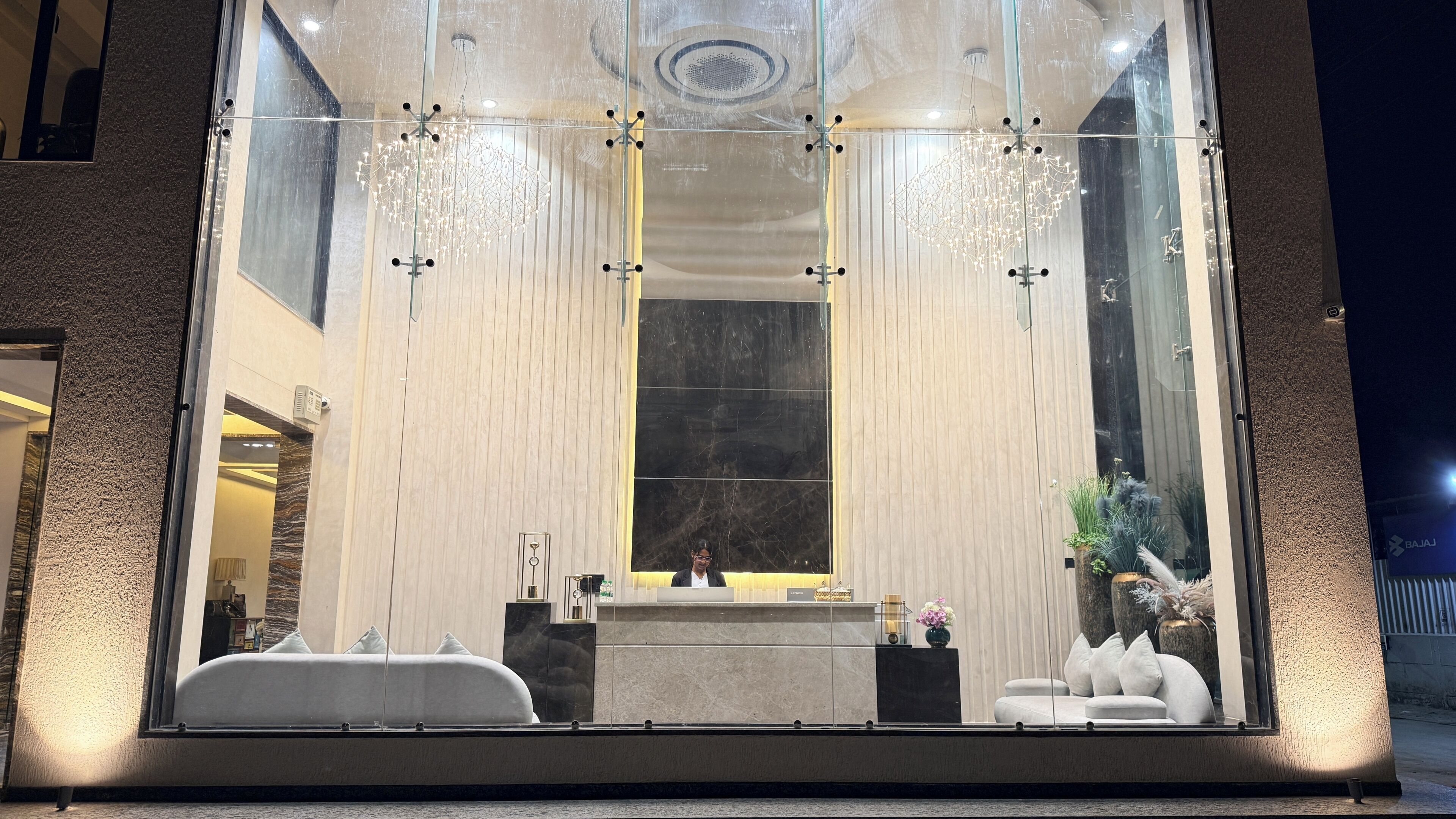 A modern hotel lobby with a reception desk, seating area, and decorative lighting.