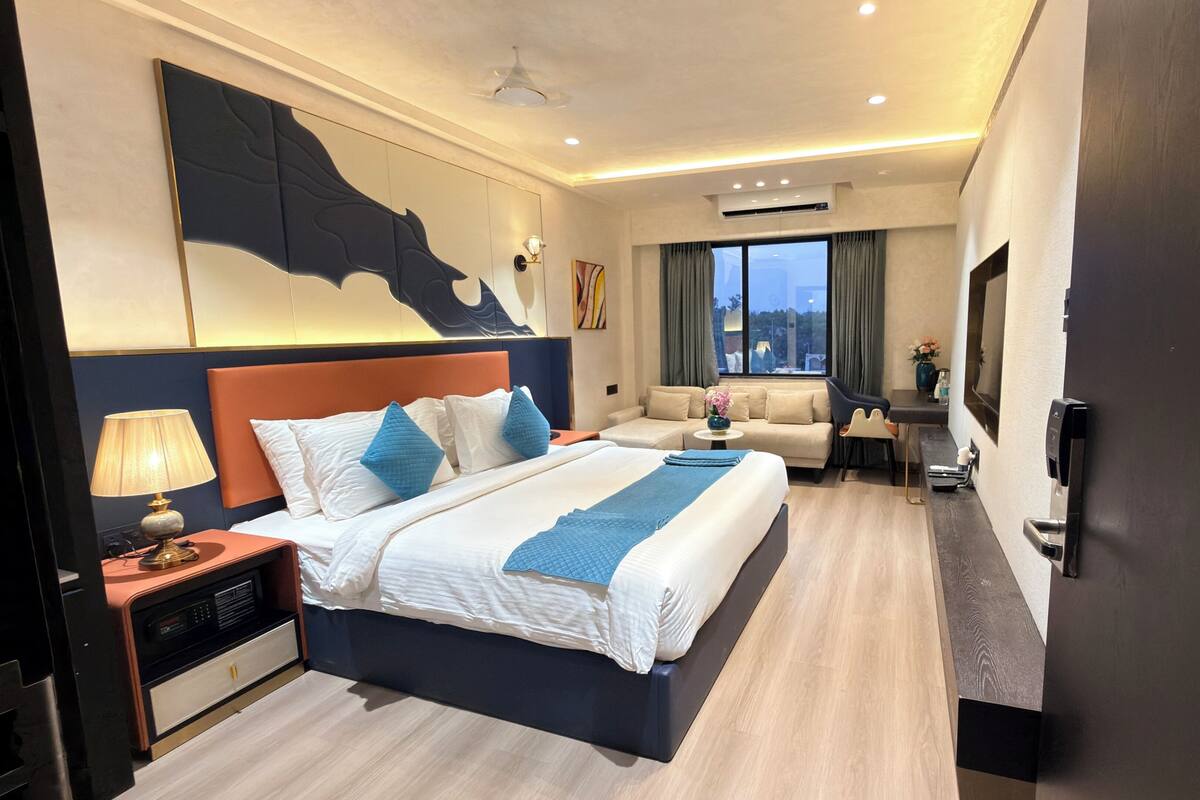 Una habitación de hotel con una cama grande, un escritorio, un sofá y una televisión.