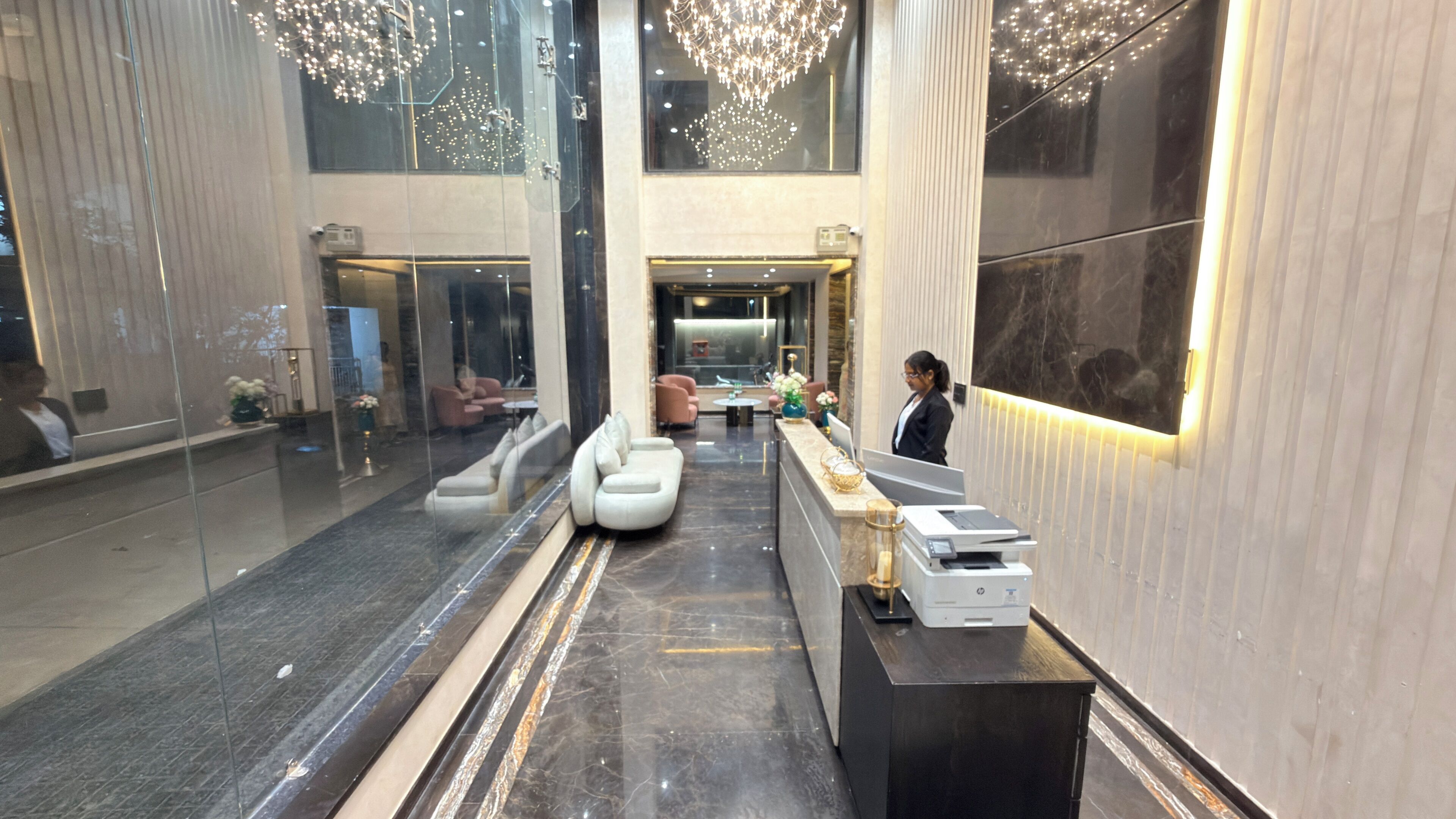 Un hall d’entrée moderne avec un comptoir d’accueil, un espace salon et un lustre.
