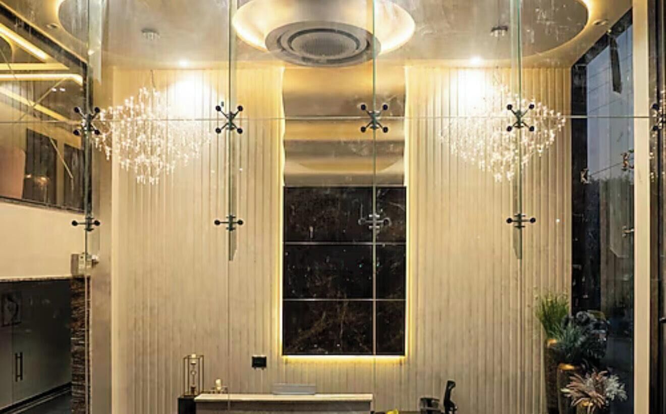 A modern bathroom with a large mirror, a chandelier, and a window.