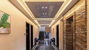 A hallway with a marble floor, recessed lighting, and a staircase at the end. - Skyearth Hotel (Indore)