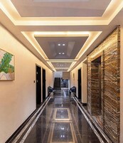 A hallway with a marble floor, recessed lighting, and a staircase at the end.