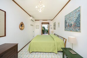 A bedroom with a bed, a dresser, a lamp, and a painting on the wall. - Villa Giovannella, Capri (Capri)