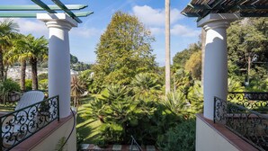 Ein Gartenbereich mit weißen Säulen, einer Pergola und unterschiedlichen Pflanzen.
