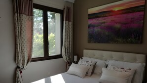 Une chambre à coucher avec un lit, des rideaux, une table de chevet et un tableau.
